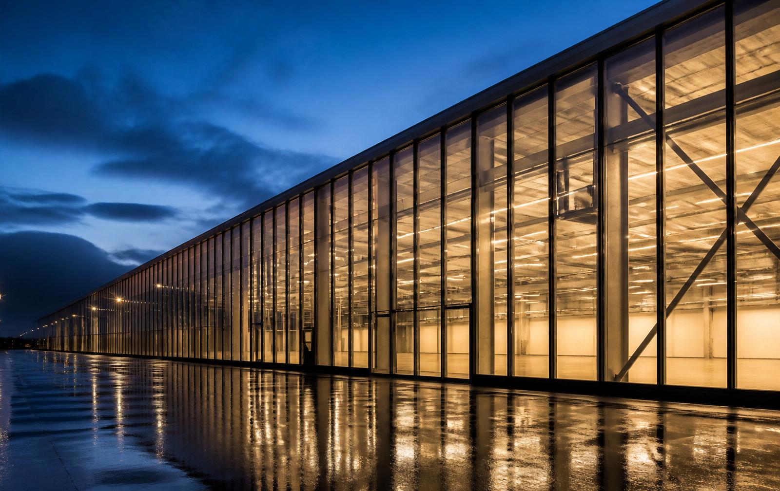 Facciata continua vetrata industriale al blue hour con montanti verticali in alluminio